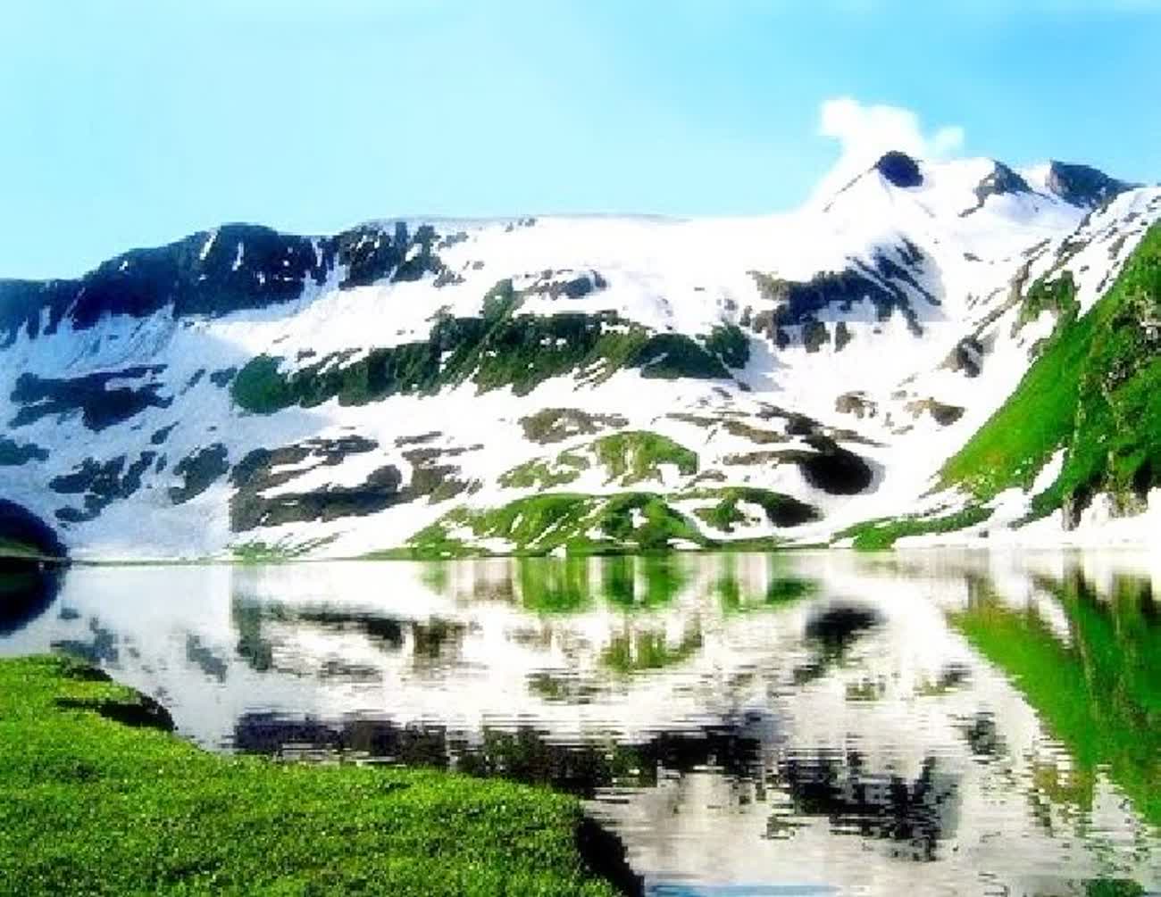 Snow-capped Himalayan peaks reflected in a still alpine lake in Kashmir